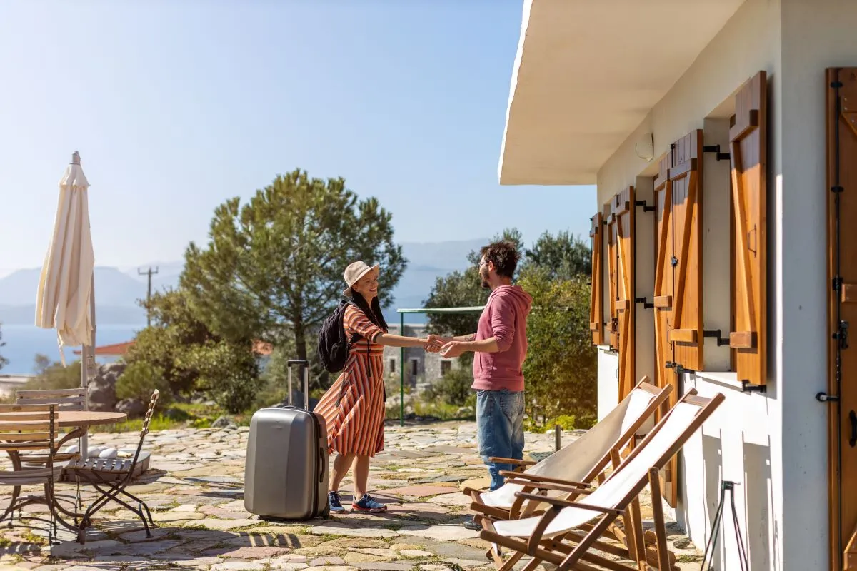 A host greeting a renter at a rented home in Greece